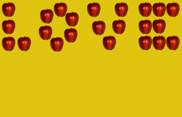 The word love made from red apples on a yellow background. Fruits. Holiday.