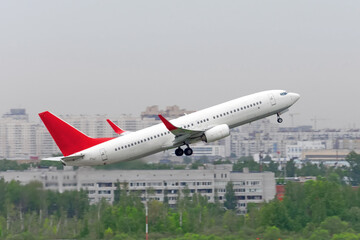 Airport near the city. The plane takes off against the backdrop of multi-storey buildings, cityscape.