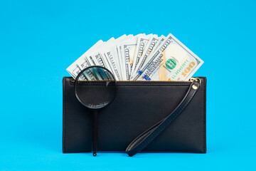Black wallet with one hundred dollar bills and two hundred euro bil on a blue background. Checks...