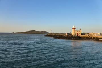 Fototapeta premium Beautiful view of Howth lighthouse and Ireland's Eye with perfectly clear evening blue sky viewed from Howth harbor, Dublin, Ireland