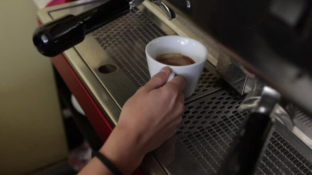 The girl takes a cup of coffee and puts it on a tray. Espresso coffee.