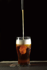 Glass of golden beer in. a dark background
