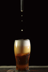 Glass of golden beer in. a dark background