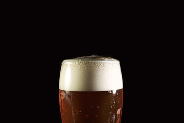 Glass of golden beer in. a dark background
