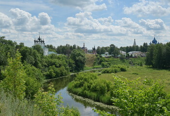 Fototapeta na wymiar Orthodox Russian churches standing along the river, pleasant summer village landscape. The 