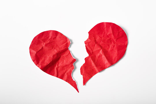Pieces of crumpled and torn red heart shape paper isolated on white background. Broken heart concept.