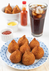 Typical brazilian snack coxinha on a plate with soda glass