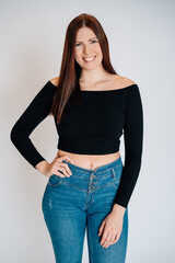 Frau mit braunen Haaren schwarzem Top Bauchrei blaue Jeans freundlich nett sedcard studio weißer hintergrund