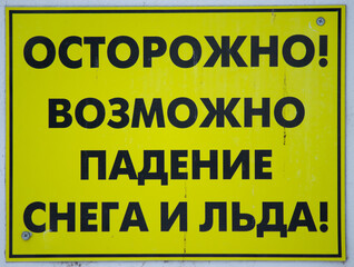 Warning on a residential building: caution snow and ice may fall. yellow sign