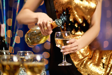 close-up of female hand with is pouring champagne into a glass. party and holiday celebration