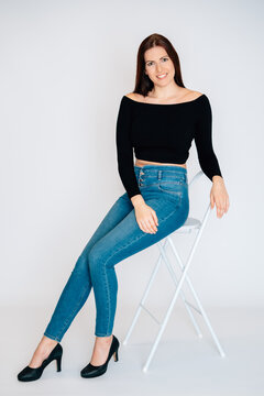 Frau mit braunen Haaren schwarzem Top Bauchrei blaue Jeans freundlich nett sedcard studio wei&szlig;er hintergrund