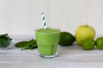 Healthy green smoothie with spinach, avocado, lime, pinapple   on wooden table