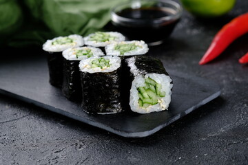 Vegetarian sushi roll with cucumber on black background