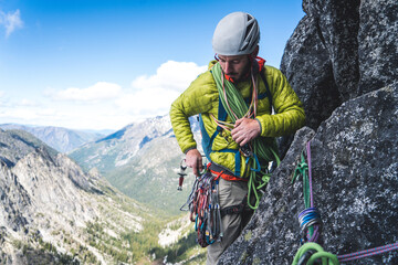 Man sorting through gear on harness while rock climbing in Washington