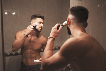 A young man begins to shave by hitting his beard with his shaving brush