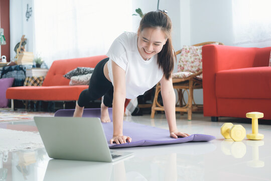 Fit woman doing yoga plank and watching online tutorials.