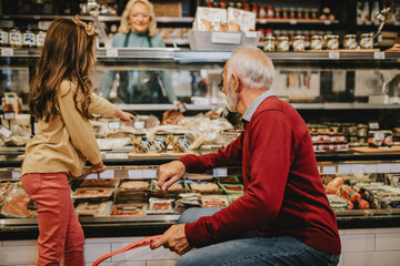 Happy grandfather shopping together with his granddaughter in grocery store or supermarket.