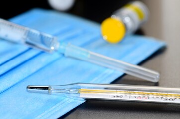 Coronavirus vaccine with syringe drugs for the design of information materials on the benefits of vaccination against viral diseases, thermometer and medical mask are the main working tools a doctor
