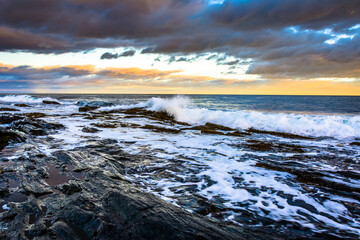 Waves splashing on rocks at sunset