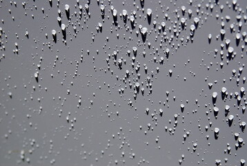 large and small rain drops on metal surface in the sun with nice shadows