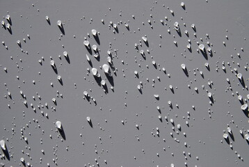 mainly large rain drops on metal surface in the sun with nice shadows