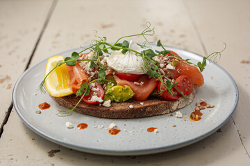 Smoked salmon and avocado on toast, topped with poached egg and dressing