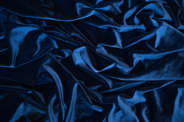 Dark blue silk satin fabric background. Delicate wavy folds. Abstract textile texture. Copy space for your design.
