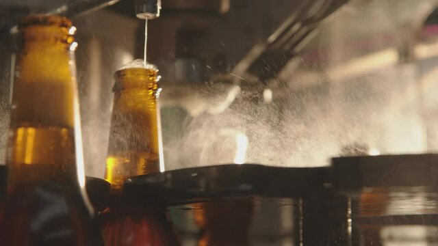 Beer filling production line. Modern glass bottle filler machine. Foam overflowing the beer bottles. Factory, brewery concept.