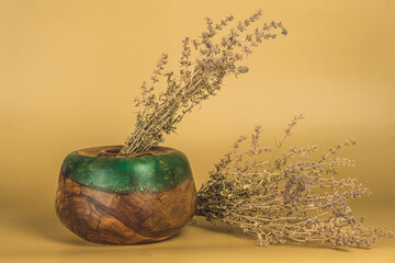 vase made of wood and epoxy resin with dry plants on a yellow background. style, decor, life style