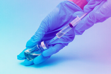 hands in blue gloves fill a syringe with a test tube of vaccine for vaccinations. the concept of...