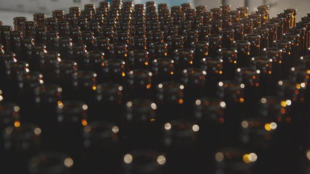 Rows of empty brown glass bottles that are prepared for the next step in a factory process. Close-up of glass bottles from above.  Factory concept.