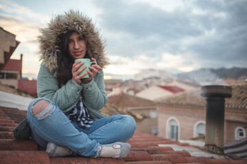 Fototapeta premium Woman in a moment of relaxation drinking tea on the roof her house