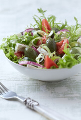 Salad with Green Olives, Tomatoes and Feta Cheese. Bright wooden background. 