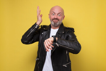 Mature caucasian man looking at his watch in panic being late on yellow wall.