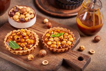 Mini tarts with hazelnuts and caramel cream filling. Sweet homemade dessert.
