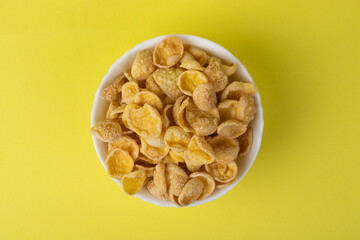 A bowl of cornflakes on a yellow background.
