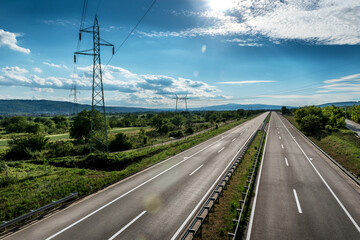 Fototapeta premium Empty silent Asphalt highway road with beautiful sky and a row of electricity pylons
