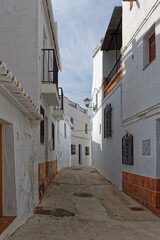 Fototapeta na wymiar A narrow street of terraced traditional Spanish Houses, shaded from the midday sun in the Montain Village of Sayalonga in Andalucia.