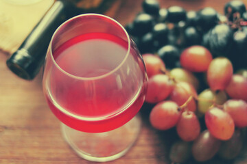 Glass of wine, bottle, grapes on a background of boards.