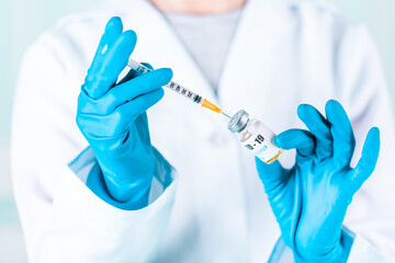 Woman doctor or nurse in uniform and gloves wearing face mask protective in lab holding medicine vial vaccine bottle with COVID-19 Coronovirus vaccine label