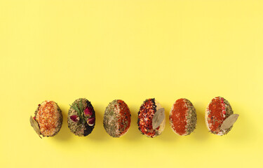 Easter concept with eggs decorated with different spices and cereals without dyes and preservatives on yellow background, Space for text