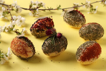 Easter concept with eggs decorated with different spices and cereals without dyes and preservatives on yellow background. Closeup. Horizontal format