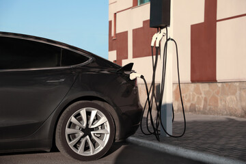 Charging modern electric car from station outdoors