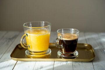 a a cup of coffee with glass of orange juice on a gold tray. sunny morning. Selective focus. High quality photo