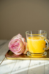 a glass of orange juice and a rose on a gold tray. Selective focus. High quality photo