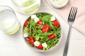 Delicious salad with arugula and vegetables on white table, flat lay