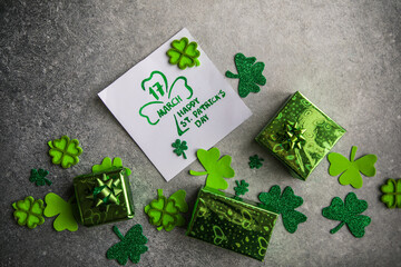 Decorative clover leaves, green gifts box, coins on stone background, flat lay. St. Patrick's Day...