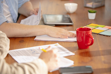 Fototapeta premium Writing notes. Close up hands of colleagues working together in a office using modern devices during creative meeting. Stationery, laptop, documents during work. Concept of business, office, finance.