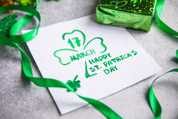 Decorative clover leaves, green gifts box, coins on stone background, flat lay. St. Patrick's Day celebration. Card Happy St. Patrick's Day