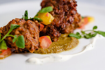 Onion bhaji with chili sauce on a white plate